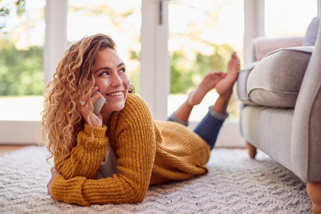 Image of woman in warm jumper lying on floor at home talking for Carrig Energy Consultancy home page.